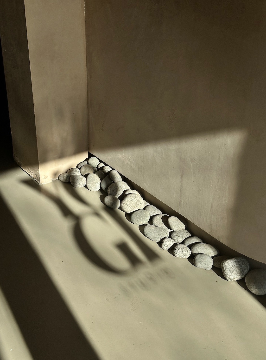 Morning light casting the YOGI logo shadow beside river stones