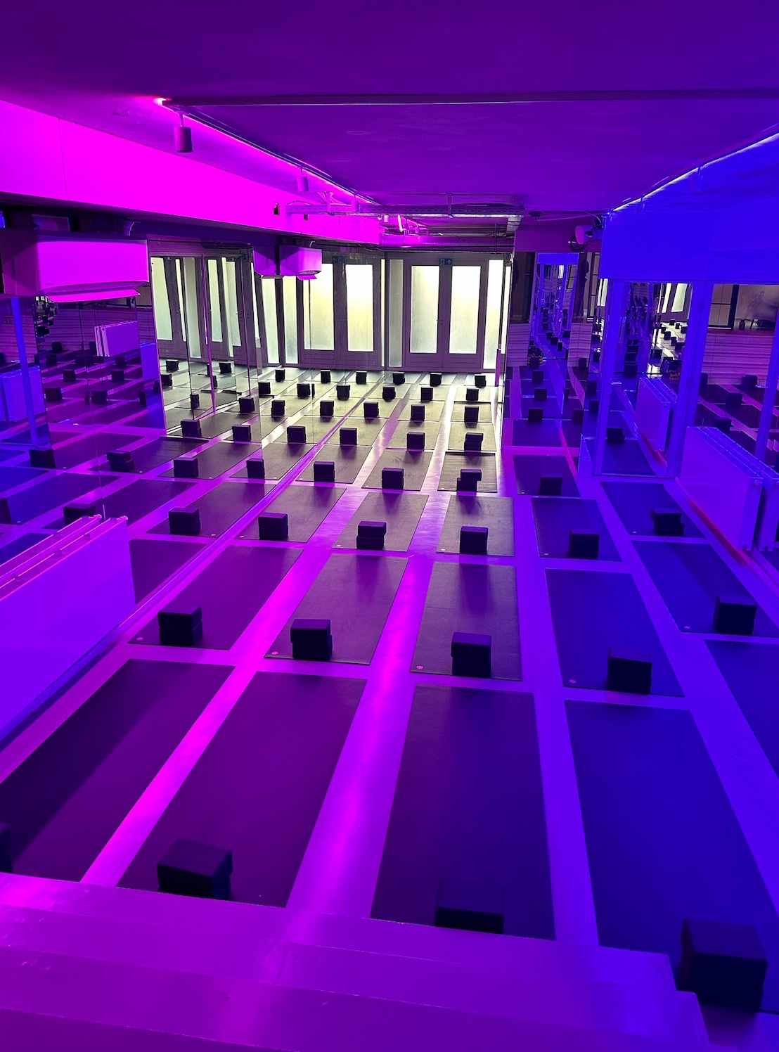 Studio 1 set up with rows of mats and blocks under purple and blue light